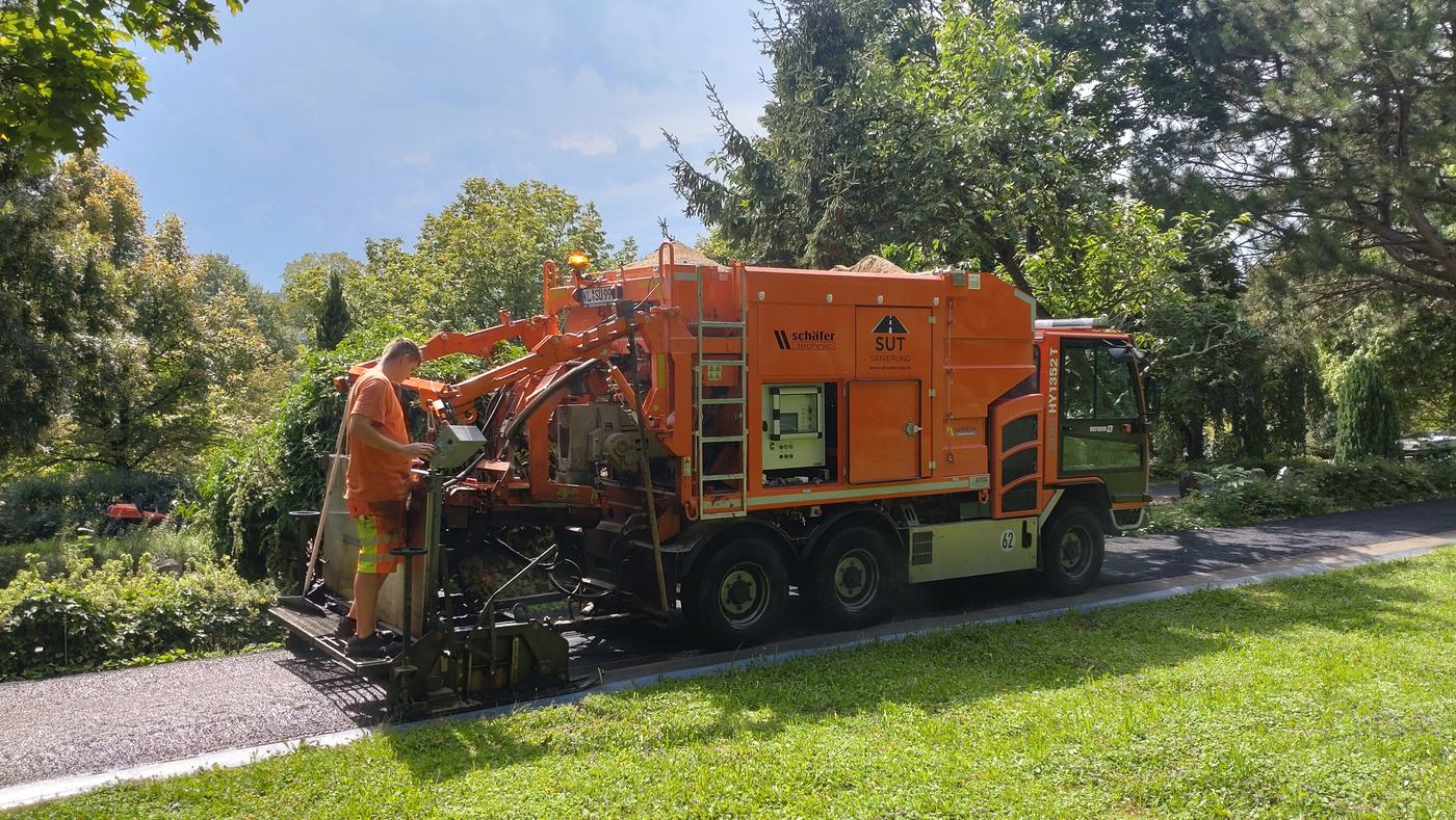 Mitarbeiter der SUT Asphalt-Kolonne am Einbaufahrzeug bei der Dünnschichtasphalt-Sanierung